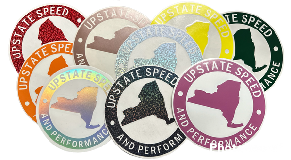 Various colors of round, vinyl, 6 inch Upstate Speed logo stickers.